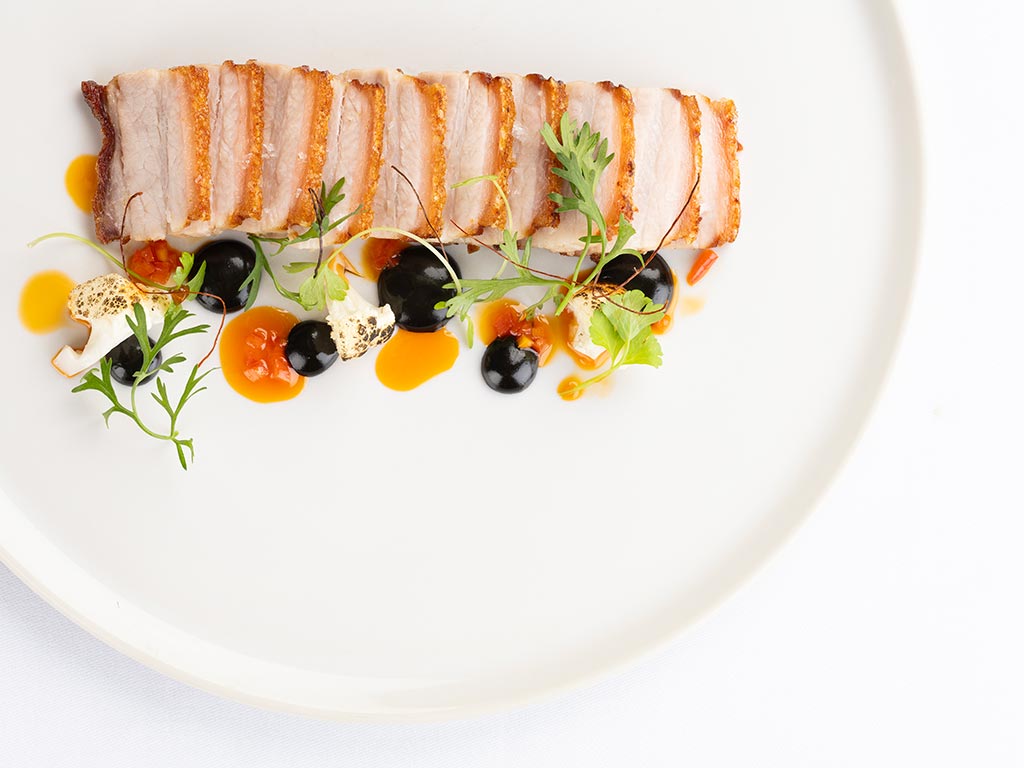 Un plato blanco con un trozo de carne encima.