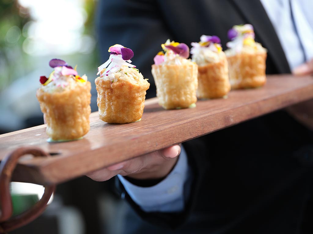 Un hombre sostiene una bandeja con aperitivos.